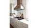 Modern kitchen with white cabinets, a wooden range hood, and quartz countertops at 1056 Capersview Ct, Awendaw, SC 29429