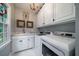 Laundry room with white cabinets, marble countertops, and modern washer/dryer at 6949 Maybank Hwy, Wadmalaw Island, SC 29487
