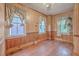 Empty dining room with wood walls and floors, and two windows with curtains at 380 Ashley Ave, Charleston, SC 29403