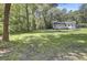 Large backyard with a white house, trampoline, and mature trees at 1586 Highway 15, Saint George, SC 29477