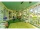 Relaxing screened porch with green flooring, ceiling fan, and views of the yard at 8083 Point Of Pines Rd, Edisto Island, SC 29438