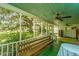 Screened porch with wooden bench, green flooring, ceiling fan, and yard views at 8083 Point Of Pines Rd, Edisto Island, SC 29438