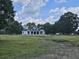White farmhouse with a metal roof, columns, and a large yard at 210 Oyster Catcher Ln, Ravenel, SC 29470