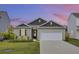 Tan house with a dark brown roof, white garage door, and landscaping at 182 Greenwich Dr, Summerville, SC 29486