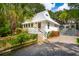 Quaint white cottage with metal roof, landscaping and a gravel driveway at 933 Mccants Dr, Mount Pleasant, SC 29464