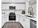 Modern white kitchen with stainless steel appliances and farmhouse sink at 120 Blossom St, Goose Creek, SC 29445