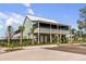 Two-story light green home with screened porches and palm trees at 9844 Haven Loop, Johns Island, SC 29455