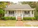 Front view of a charming white cottage with rocking chairs on the porch at 309 Wintergreen Rd, Walterboro, SC 29488