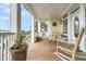 Relaxing porch with rocking chairs, potted plants, and white railings at 1408 Palmetto Blvd, Edisto Island, SC 29438