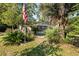 Single-story house with a screened porch, lush landscaping, and an American flag at 115 Galloway Ct, Moncks Corner, SC 29461