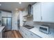 White kitchen boasts stainless steel appliances, gray tile backsplash, and wood flooring at 145 Hedera Ct, Summerville, SC 29486