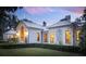 White exterior home with metal roof, lit windows, and landscaping at dusk at 4285 Clover Hill Rd, Green Pond, SC 29446