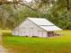 Large white barn with a metal roof and a porch in a grassy field at 4285 Clover Hill Rd, Green Pond, SC 29446