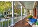 Inviting front porch with white columns, wooden flooring, and comfortable seating, overlooking a tree-lined street at 20 Perseverance St, Mount Pleasant, SC 29464