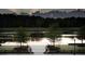Serene lakefront view with a wooden dock, benches, and lush greenery at 3904 Delinger Dr, Mount Pleasant, SC 29466