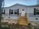 Mobile home with gray siding, white door, and wooden steps at 317 Marion Rd, Dorchester, SC 29437