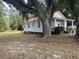 Side view of a white cottage nestled under a large oak tree at 507 E 5Th N St, Summerville, SC 29483