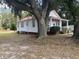 Side view of a white cottage with red trim, under a large oak tree at 507 E 5Th N St, Summerville, SC 29483