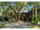 Two story home exterior with a large oak tree, gravel driveway, and lush landscaping at 4239 Tom Point Rd, Hollywood, SC 29449