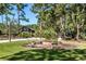 Brick fire pit surrounded by wooden chairs in a lush backyard at 4239 Tom Point Rd, Hollywood, SC 29449