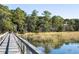 Wooden dock extending over tranquil water, offering scenic views of marsh grasses and lush greenery at 4239 Tom Point Rd, Hollywood, SC 29449
