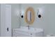 White vanity with marble countertop, circular rattan mirror, and wall sconces at 5209 Seewee Rd, Awendaw, SC 29429