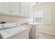 Bright laundry room with white cabinets, washer, dryer, and utility sink at 5250 Timber Race Crse, Hollywood, SC 29449