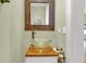 Small powder room with glass vessel sink, wooden vanity, and decorative mirror at 2873 Maritime Forest Dr, Johns Island, SC 29455