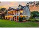 Two-story home with a large deck, lights, and beautifully landscaped yard at dusk at 2873 Maritime Forest Dr, Johns Island, SC 29455