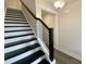 Modern staircase with black and white striped treads and a sleek metal railing at 341 Bremerton Dr, Goose Creek, SC 29445