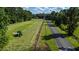 Aerial view of farm land with tractor, showing a long field, a road, and surrounding trees at 0 Tuten Road, Round O, SC 29474
