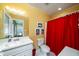 Bright bathroom with shower/tub combo, white vanity, and red shower curtain at 2302 Palmetto Blvd, Edisto Beach, SC 29438