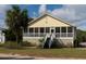 Front view of yellow house with screened porch and palm tree at 2302 Palmetto Blvd, Edisto Beach, SC 29438