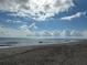 Sandy beach with ocean waves under a partly cloudy sky at 2302 Palmetto Blvd, Edisto Beach, SC 29438