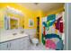 Bathroom with white vanity, toilet, and shower with colorful curtain at 2302 Palmetto Blvd, Edisto Beach, SC 29438