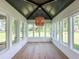 Sunroom with walls of windows, hardwood floors, and a unique chandelier at 3881 Summerton St, Mount Pleasant, SC 29466