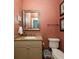 Small bathroom with beige vanity, coral walls, and a framed mirror at 362 Pelican Flight Dr, Dewees Island, SC 29451