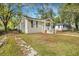 Tan house with white porch and steps, surrounded by trees and a yard with fallen leaves at 2674 Houston St, North Charleston, SC 29405