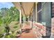 Inviting front porch with brick flooring, columns, and green shutters at 203 Hickory Nut Drive, Harleyville, SC 29448