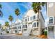 Row of townhouses with various pastel colors, palm trees, and attached garages at 108 W 2Nd St, Folly Beach, SC 29439