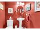 Small bathroom with red walls, white pedestal sink, and oval mirror at 105 Queensbury Cir, Goose Creek, SC 29445