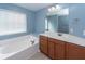 Main bathroom with soaking tub, wood vanity, and light blue walls at 9044 Parlor Dr, Ladson, SC 29456