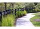 Curving sidewalk pathway with lush landscaping and black fence at 104 True Blue, Summerville, SC 29486