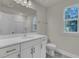 Bathroom features a white vanity with gold accents, a large mirror, and a window at 5629 Ellington School Rd, Ravenel, SC 29470