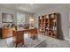 Home office with wood desk, bookcase, and comfortable chair, overlooking trees at 5629 Ellington School Rd, Ravenel, SC 29470