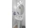 Small bathroom with pedestal sink, round mirror, and light fixtures at 488 Sanctuary Park Dr, Summerville, SC 29486