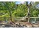 Relaxing hammock nestled between trees in a fenced backyard with teal chairs at 825 Harbor View Rd, Charleston,  29412