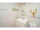 Bathroom with white vanity, mirror, and playful lobster and flip-flop artwork at 108 Palmetto Blvd, Edisto Beach, SC 29438