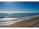 Stunning beach view with sparkling waves under a clear blue sky at 108 Palmetto Blvd, Edisto Beach, SC 29438