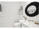Chic powder room with a round mirror, floating sink, and glass shelves at 2220 Ion Ave, Sullivans Island, SC 29482